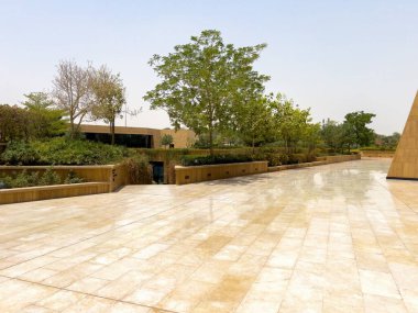 Riyad, Suudi Arabistan 'ın modern ticaret bölgesi. Suudi Arabistan 'ın Riyad kentindeki modern bir alışveriş ve ticaret bölgesinin çarpıcı manzarası. Mimari geometrik şekilleri, yeşilliği ve zarifliği harmanlıyor.