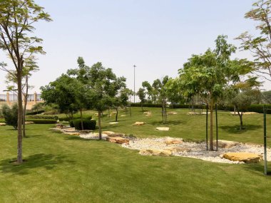 Riyad, Suudi Arabistan 'ın modern ticaret bölgesi. Suudi Arabistan 'ın Riyad kentindeki modern bir alışveriş ve ticaret bölgesinin çarpıcı manzarası. Mimari geometrik şekilleri, yeşilliği ve zarifliği harmanlıyor.