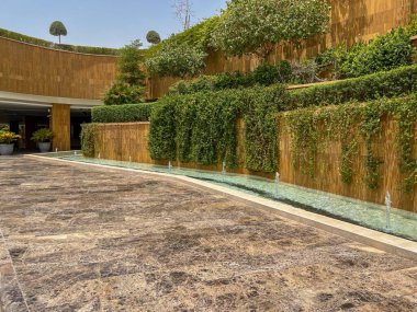 Riyad, Suudi Arabistan 'ın modern ticaret bölgesi. Suudi Arabistan 'ın Riyad kentindeki modern bir alışveriş ve ticaret bölgesinin çarpıcı manzarası. Mimari geometrik şekilleri, yeşilliği ve zarifliği harmanlıyor.