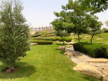 Riyad, Suudi Arabistan 'ın modern ticaret bölgesi. Suudi Arabistan 'ın Riyad kentindeki modern bir alışveriş ve ticaret bölgesinin çarpıcı manzarası. Mimari geometrik şekilleri, yeşilliği ve zarifliği harmanlıyor.