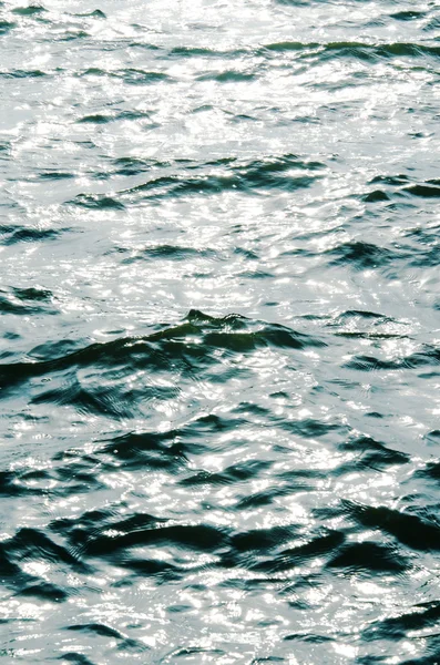 Textura da água ondulada do rio que reflete os raios solares — Fotografia de Stock
