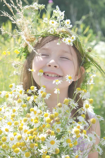 Pequena menina feliz em uma grinalda de flores de campo no prado — Fotografia de Stock