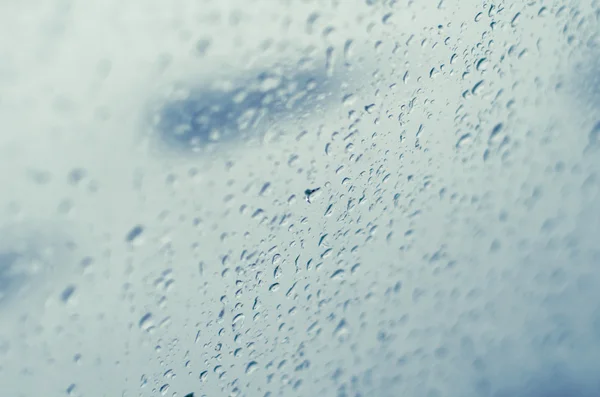 Raindrops on window glass, toned blue, tilt shift