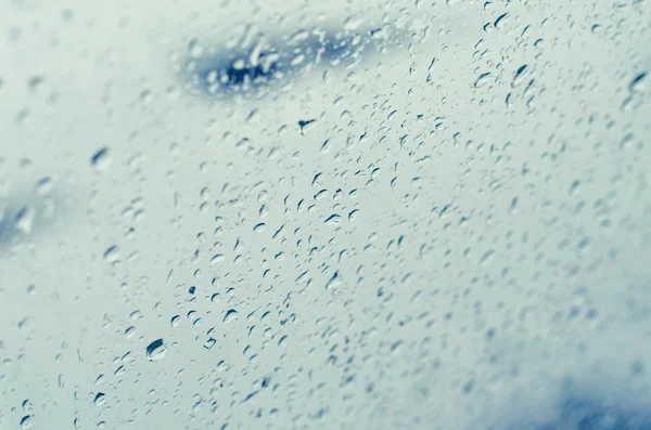 Regentropfen auf Fensterglas, blau getönt — Stockfoto