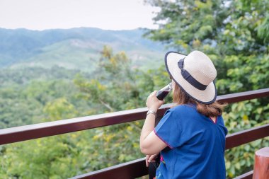 Yetişkin Asyalı bir kadının dut suyu ya da şişe bardağında taze arınma böğürtlen suyu içmesine odaklanın. Bir bayram boyunca dinlenen ve dağlara bakan bir kadın..