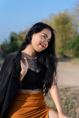 Gülümseyen ve şık kıyafetler giyen mutlu genç bir kadının portresi. Açık havada vücudunda dövmesi olan seksi poz veren genç bir model. Yaşam tarzı ve olumlu insani duygu kavramı.