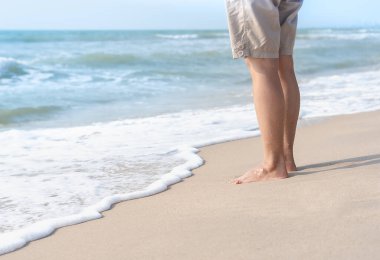 Genç bir kadının çıplak ayaklarıyla gelen ve egzotik doğaya seyahat etmekten zevk alan bir dalga. Yazın kumlu sahilde çıplak ayakla duran damlacıkları olan güzel sağlıklı kadın bacakları. Yaşam tarzı kavramı