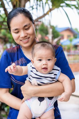 Mutlu çocuk ve genç bir kadının, dışarıda erkek bebeği tutmasına odaklan. Yeni doğmuş bebek torunu olan güzel bir Asyalı kadın. Aile ve sağlık hizmeti kavramı