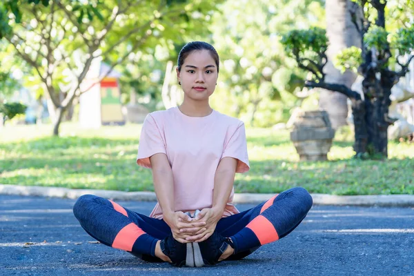 公園でストレッチ運動をする幸せな若いフィットネス女性 アジアの女性は朝のランニングやワークアウトの前に暖まるために腕や足を伸ばしています 健康とライフスタイルのコンセプト — ストック写真