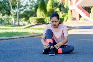 Koşu ayakkabısı bağlayan ve koşmadan önce sokakta oturan sağlıklı genç bir kadının portresi. Bayan atlet koşuyor ve dışarıda antrenman yapıyor. Rahatlama, doğayla uyum. Sağlıklı ve Yaşam Tarzı kavramı