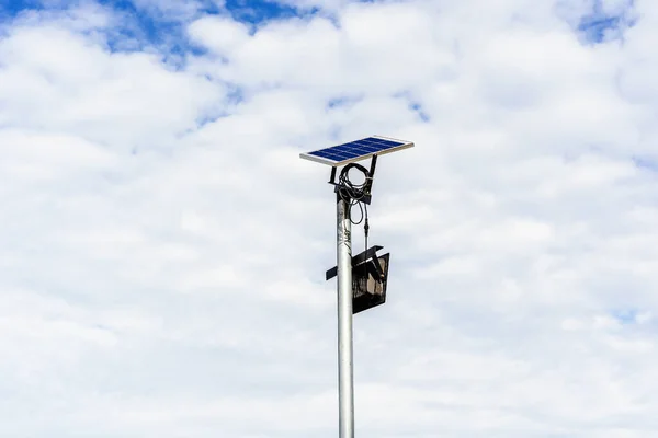 Small Solar Panel for light in street or park with white clouds and blue sky. Outdoor lighting pole with small size solar panel power by themself, new technology and energy trend for public area