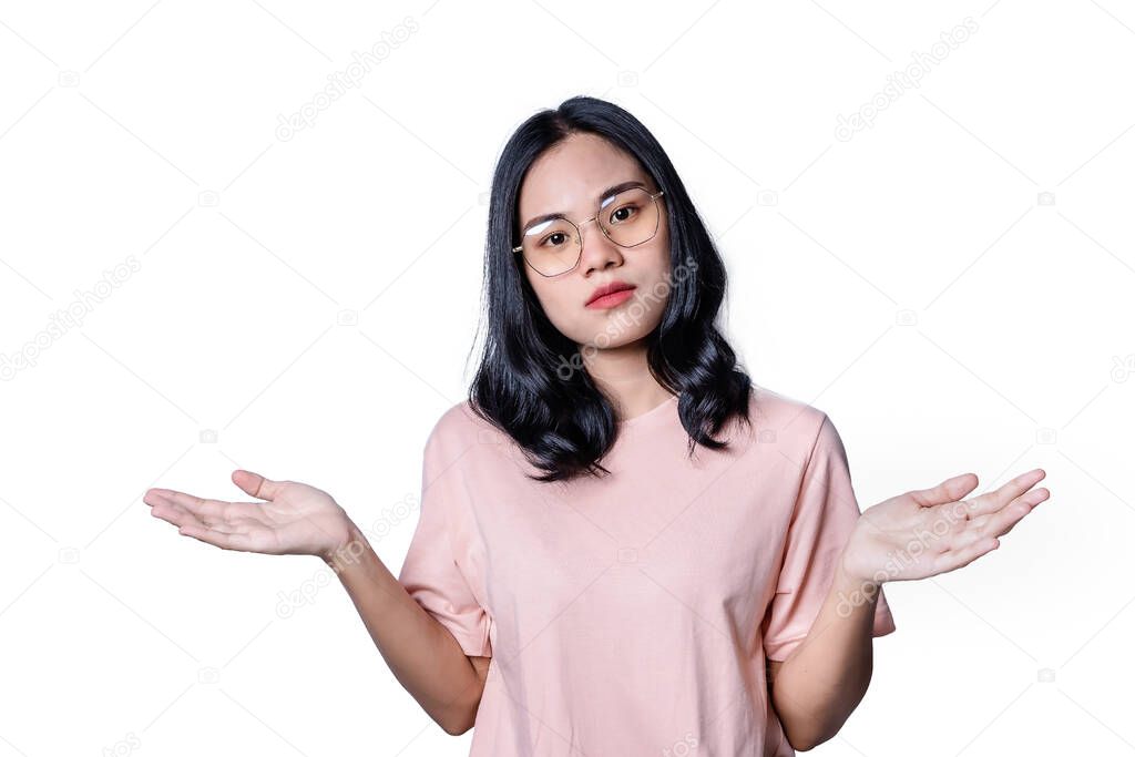 Doubtful young woman wearing glasses shrugging shoulders and spreads hands, feeling confused, lifting hands, unsure about problem, puzzled young female looking at camera isolated on white background.