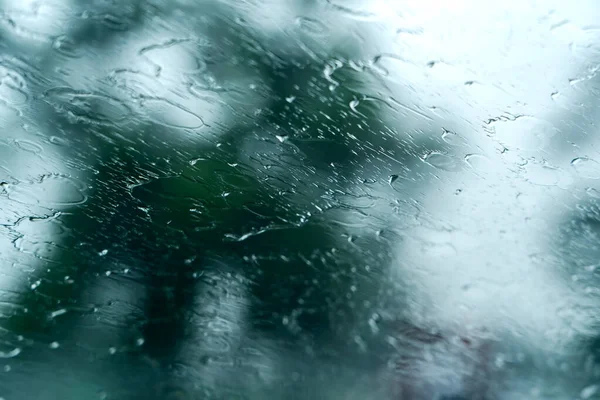 Rain waters on glass of car unique blurry photo, traveling under rain. Abstract wet windshield on rainy days during the storm photo shot from inside car. Dangerous vehicle driving and slippery road