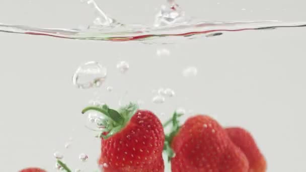 Délicieuse fraise tombant dans l'eau au ralenti beau coup commercial — Video