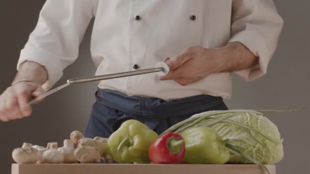 Chef affûtant son couteau devant la table des légumes Cuisinière préparant ses outils — Video
