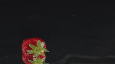Taze çilekler yavaş çekimde suya dökülüyor yansımalarla.