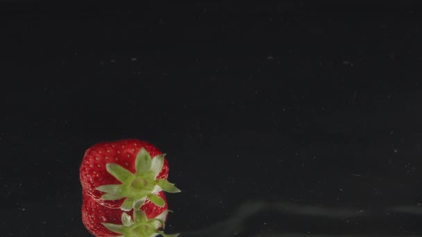 Verse aardbeien spetteren vallen in water op slow motion met reflecties — Stockvideo