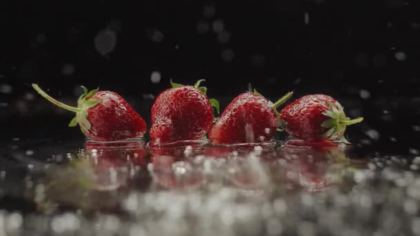 Čerstvé jahody cákající na zpomalený film s odrazy pro přírodní šťavnaté — Stock video