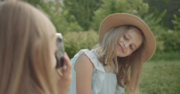 Linda menina com cabelos longos com chapéu posando para uma foto no parque — Vídeo de Stock