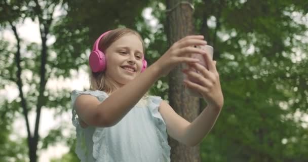 Παιδί περιήγηση στο διαδίκτυο μιλώντας στο έξυπνο τηλέφωνο Παιδί μέλι χρησιμοποιώντας ακουστικά — Αρχείο Βίντεο