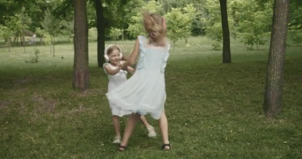 Bambini felici ballano e ascoltano musica nel parco le sorelle ruotano in modalità giorno — Video Stock