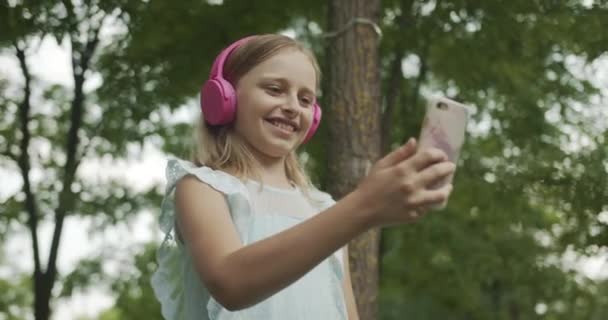 Menina beatiful usa comunicação de vídeo com áudio de som móvel e fones de ouvido — Vídeo de Stock