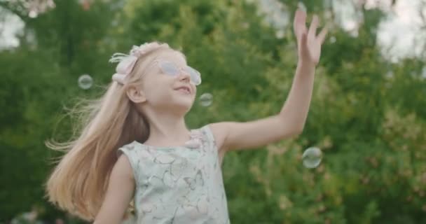 Mädchen Kind fängt Seifenblasen im Park im Freien Kinder träumen Konzept glücklich — Stockvideo