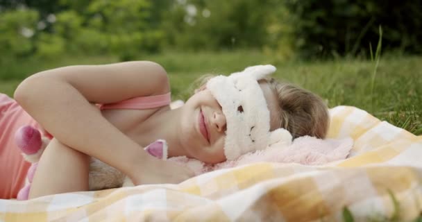 年轻的少女和睡眠面具睡在一起，她在公园里快乐地醒来 — 图库视频影像