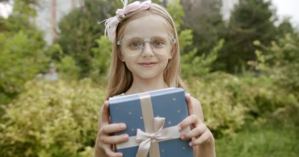 Legrační holčička s úsměvem dát dárek a usmívat se, aby on-line video hovor — Stock video