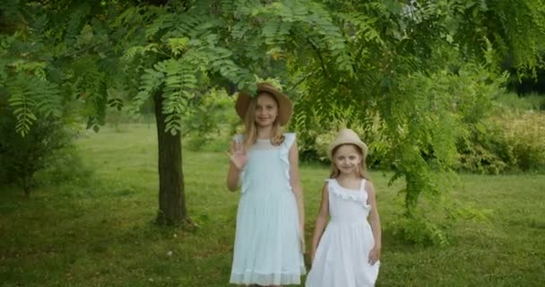 Irmãs bonitas andar ao redor do parque sorrindo dizer olá as crianças de mãos dadas — Vídeo de Stock