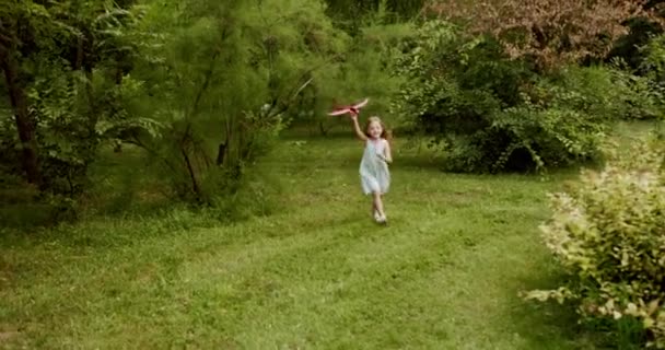 Glückliches Mädchen spielen mit einem Spielzeugflugzeug Mädchen Traumkind in der Natur hübsches kleines Kind — Stockvideo
