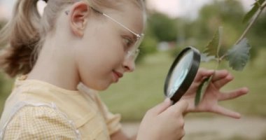 Çocuk büyüteçle keşfeder ve doğa bitkileri ve böcekleri inceler.