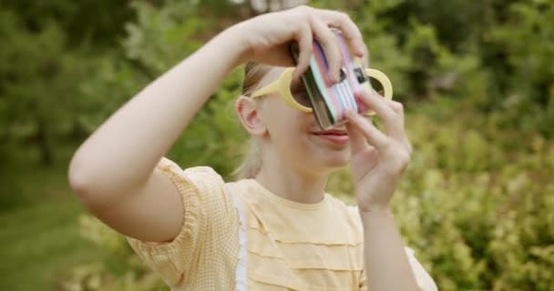 Gadis mengambil gambar dengan kamera insta dan kuning retro gaun dan kacamata modern — Stok Video