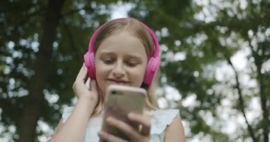 Mutlu genç, modern pembe kulaklıklardan müzik dinliyor.