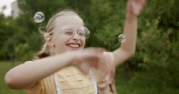 Niña alegre niño atrapa burbujas de jabón en el parque al aire libre sueño de felicidad — Vídeos de Stock