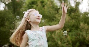 Kız çocuğu parkta sabun köpüğü yakalıyor. Çocuklar mutlu bir rüya görüyor.
