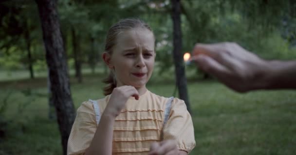 Retrato menina tem medo fogos de artifício no parque uma mão acender o fogo — Vídeo de Stock