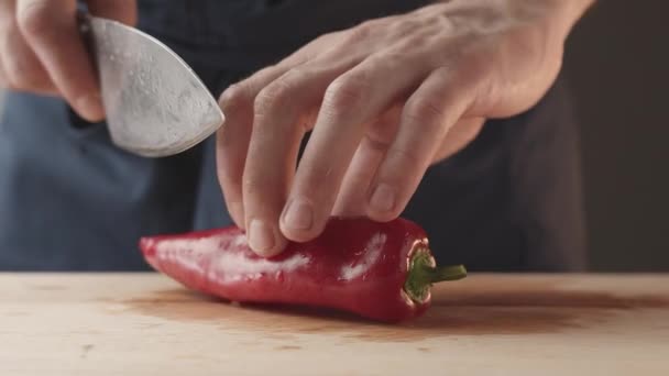 Homens Chef vira com mão pimenta vermelha com faca em um detalhe de placa de madeira preparar — Vídeo de Stock