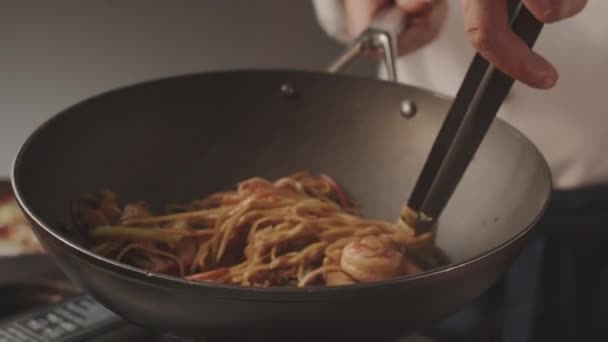 Chef bereitet Nudeln mit Gemüse mit Garnelen aus Fleisch in schwarzer eiserner Pfanne serviert — Stockvideo