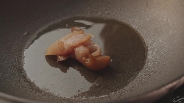 Bitar av rått kött faller för matlagning av kyckling bröst i stekning svart pan — Stockvideo