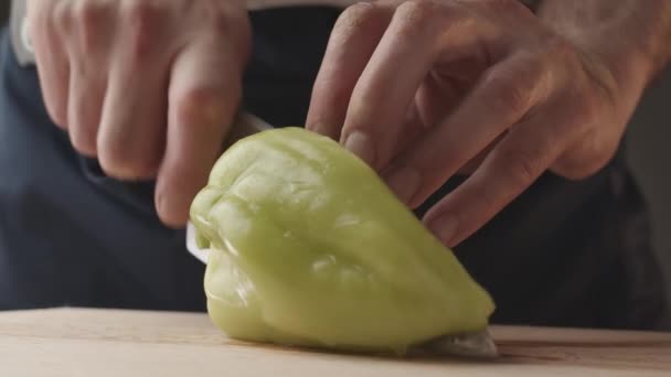 Szef kuchni cięte z nożem zielony pieprz na drewnianym detalu deski ludzka ręka — Wideo stockowe