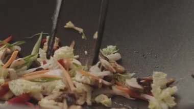 Aşçı sebzeleri zencefilli mantarlara kırmızı biber ve lahanaya karıştırır. 