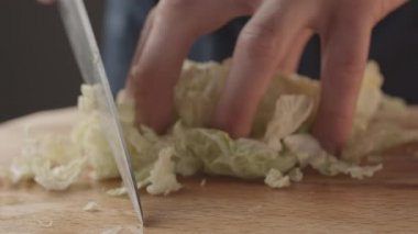 Bıçakla kesilmiş bir adam ve Çin lahanası. Salata malzemelerini hazırlıyor. 