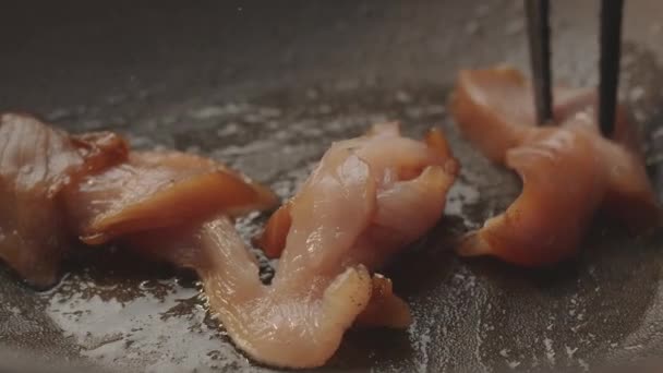 Delar av kött som beretts och bytts ut med koktänger i en stor kastrull — Stockvideo