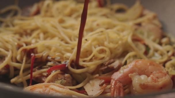 Een zoete Aziatische saus wordt gegoten over een wok gekookt in een pan zeer smakelijke noedels — Stockvideo