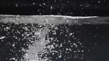 Temiz su, temiz yüzey oluşturur. Yavaş çekim, siyah arkaplana düşer.