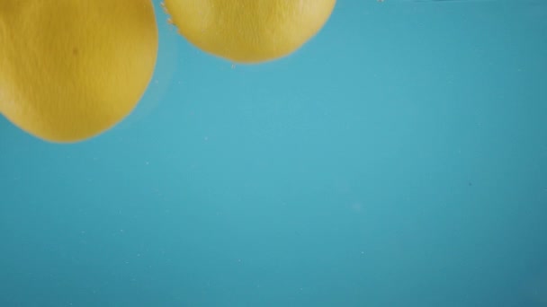 Limone giallo che cade in acqua trasparente fondo blu Frutta fresca Agrumi — Video Stock