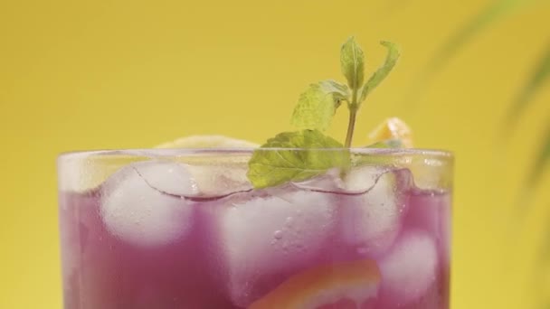 Cocktail citron violet été rafraîchissant avec de la menthe glacée sur fond jaune — Video