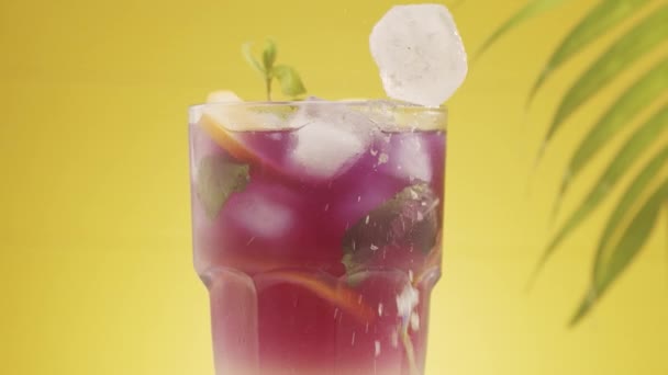 Limonade roteren cocktail verfrissend met valt ijs en munt op gele achtergrond — Stockvideo
