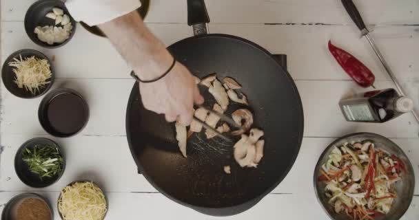 Приготовление пищи в ресторане шеф-повар готовить мясо и креветки в большой черной кастрюле вид сверху — стоковое видео